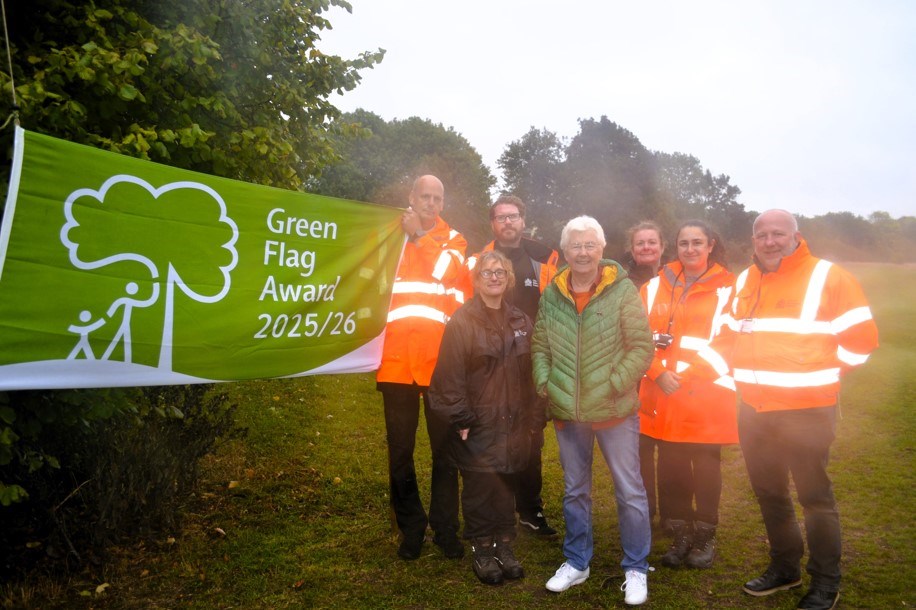 People standing around the Campsall Park Green Flag. 